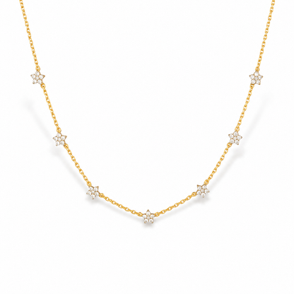A delicate gold chain necklace featuring seven small star-shaped clusters of clear stones, set against a clean white background.

