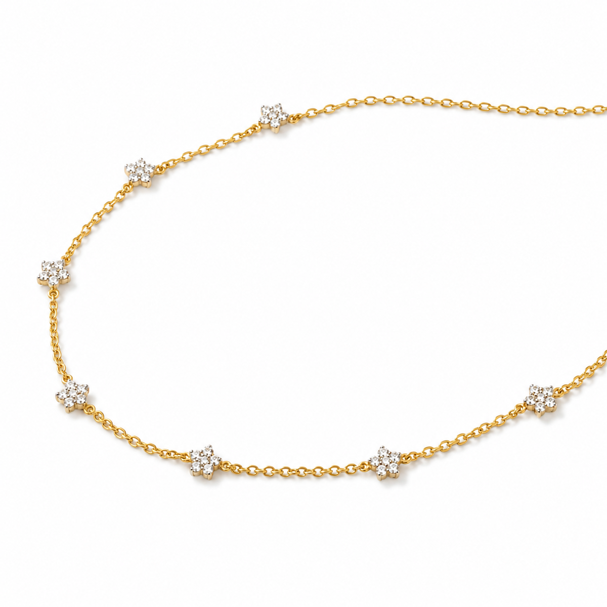 A delicate yellow gold chain necklace featuring seven small, round-cut clear gemstone clusters spaced evenly along the chain, displayed on a clean white background.

