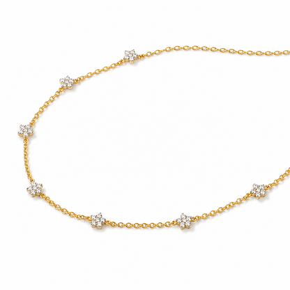 A delicate yellow gold chain necklace featuring seven small, round-cut clear gemstone clusters spaced evenly along the chain, displayed on a clean white background.

