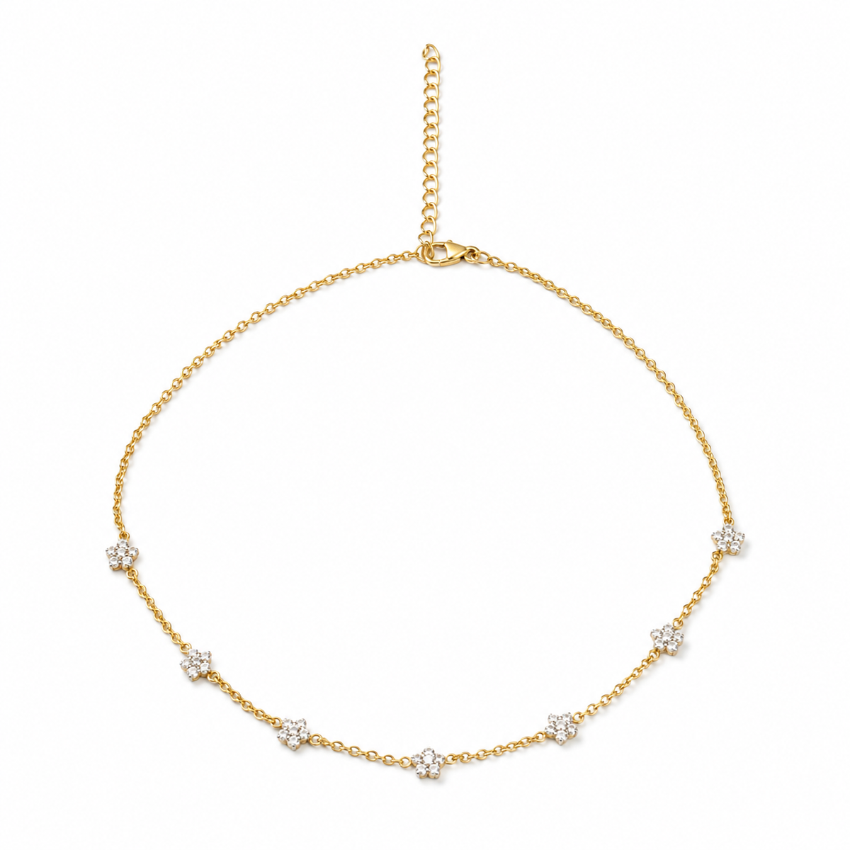 A delicate yellow gold chain necklace with seven small floral clusters of clear stones, displayed on a clean white background.

