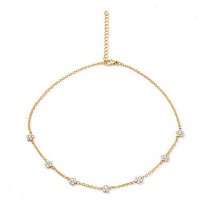 A delicate yellow gold chain necklace with seven small floral clusters of clear stones, displayed on a clean white background.

